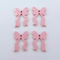 Two pairs of pastel pink bow dangle blanks laying flat