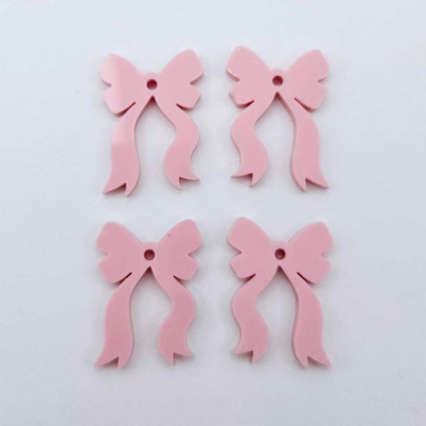 Two pairs of pastel pink bow dangle blanks laying flat