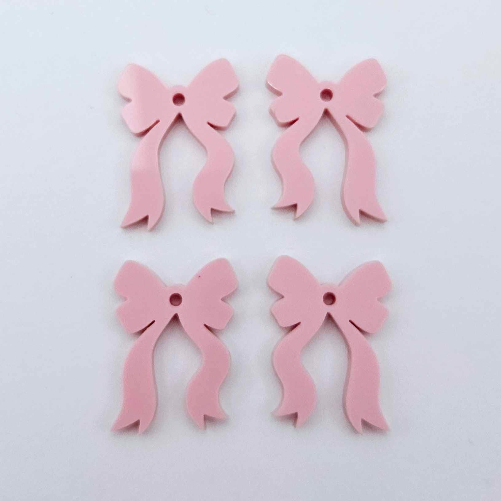 Two pairs of pastel pink bow dangle blanks laying flat