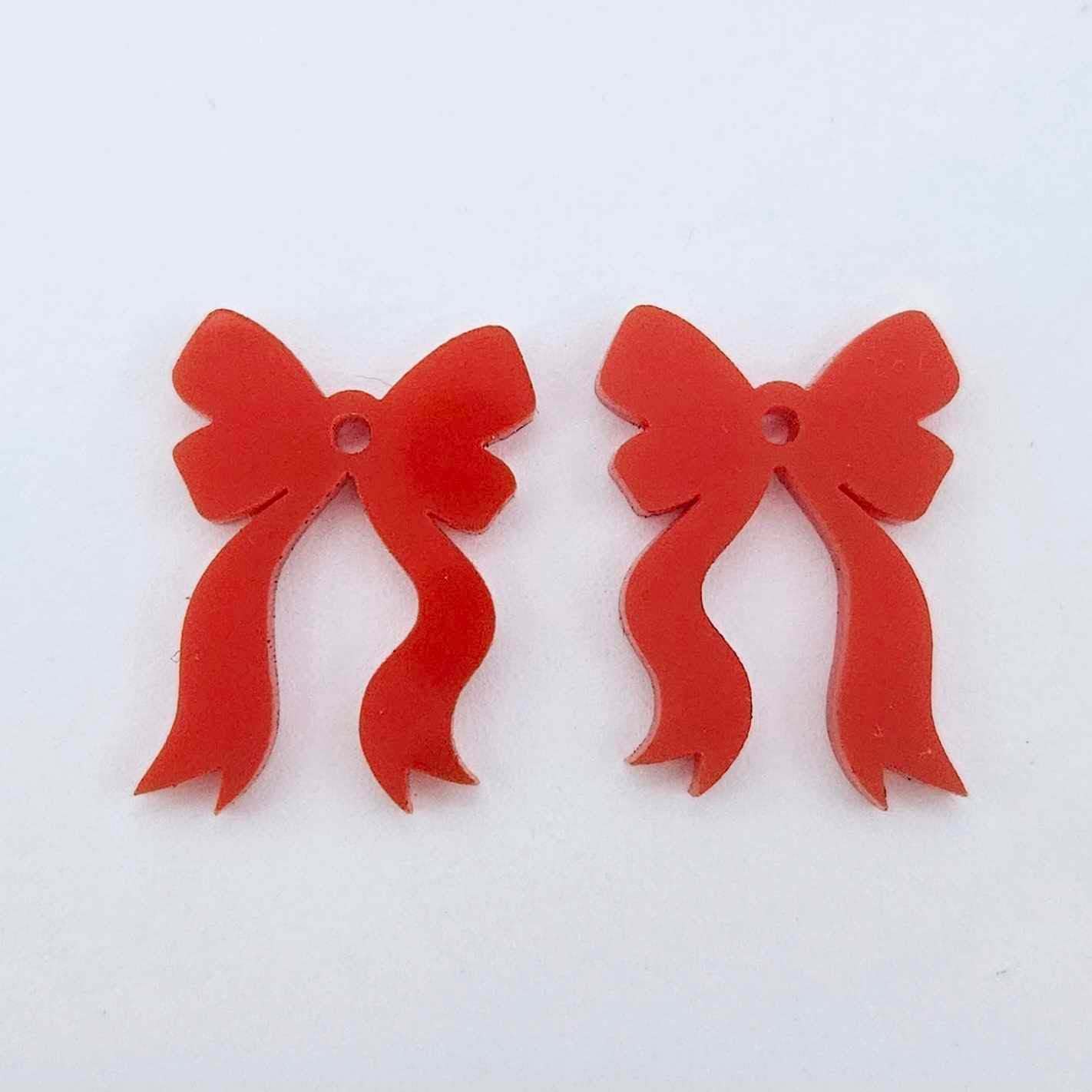One pair of solid red acrylic bow dangle earring blanks laying flat