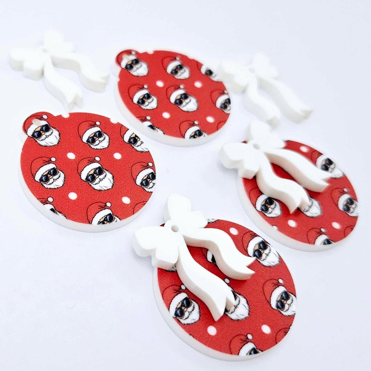 Two pairs of Jolly Cool UV printed bauble dangle blanks with included white bows laying flat