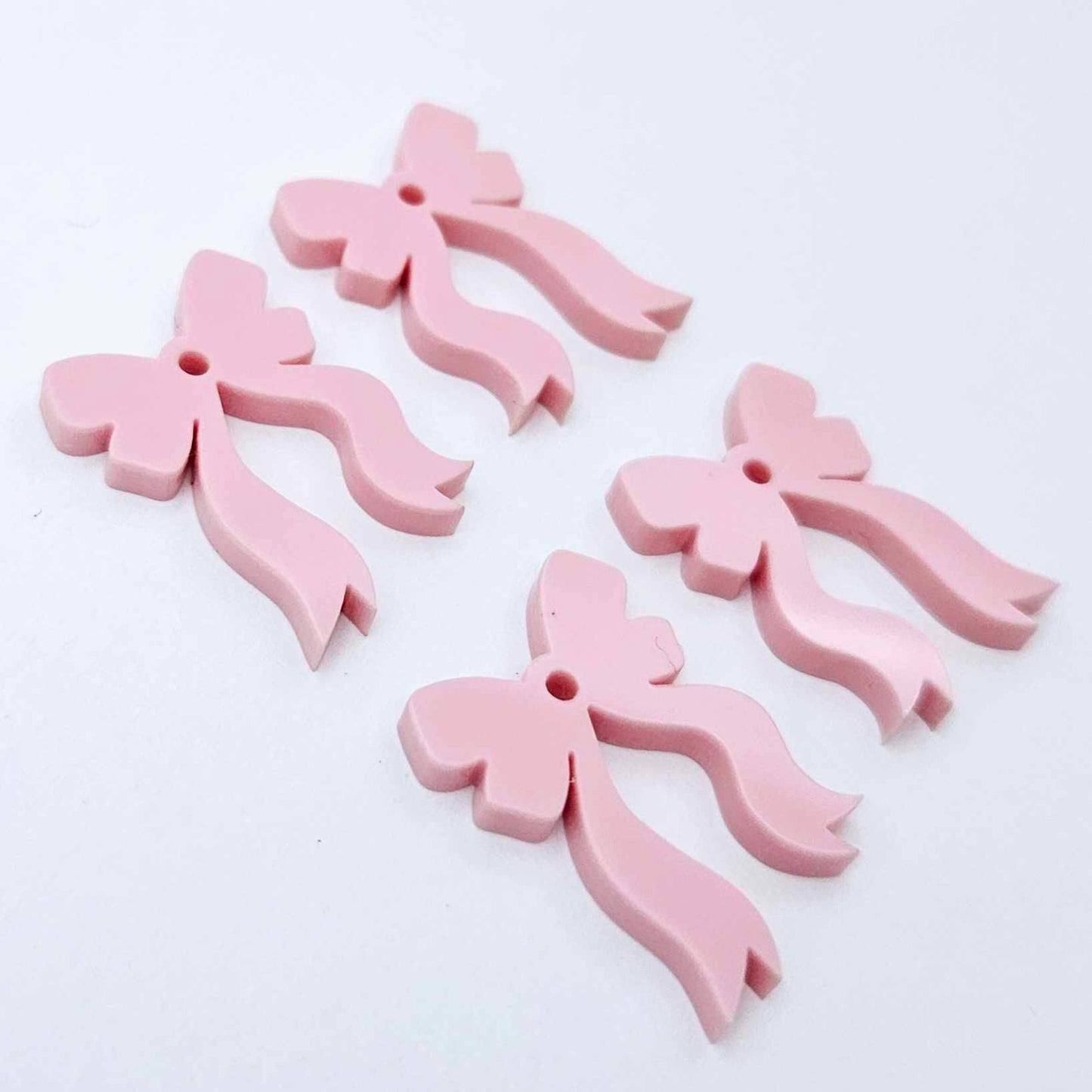 Two pairs of pastel pink bow dangle blanks laying flat