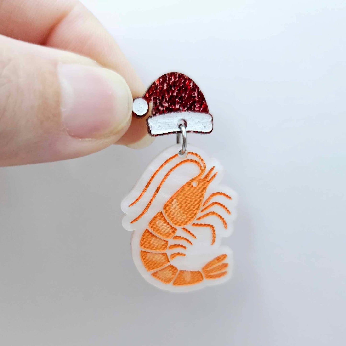 One white marble acrylic prawn dangle earring blank assembled with a Santa Hat Topper, shown as a festive Australian Christmas earring