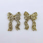One pair of gold glitter acrylic bow dangle earring blanks laying flat