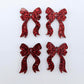 Two pairs of red glitter acrylic bow dangle earring blanks laying flat