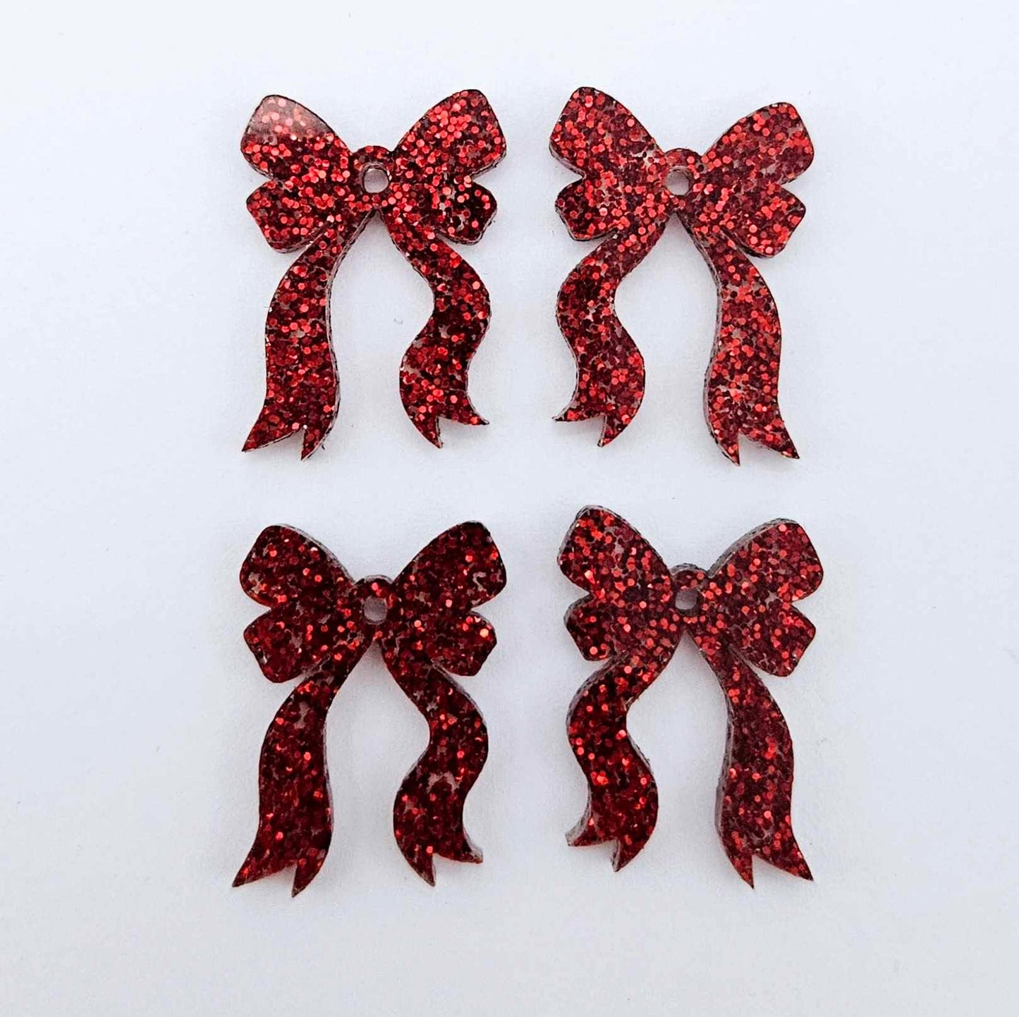 Two pairs of red glitter acrylic bow dangle earring blanks laying flat