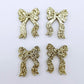 Two pairs of gold glitter acrylic bow dangle earring blanks laying flat