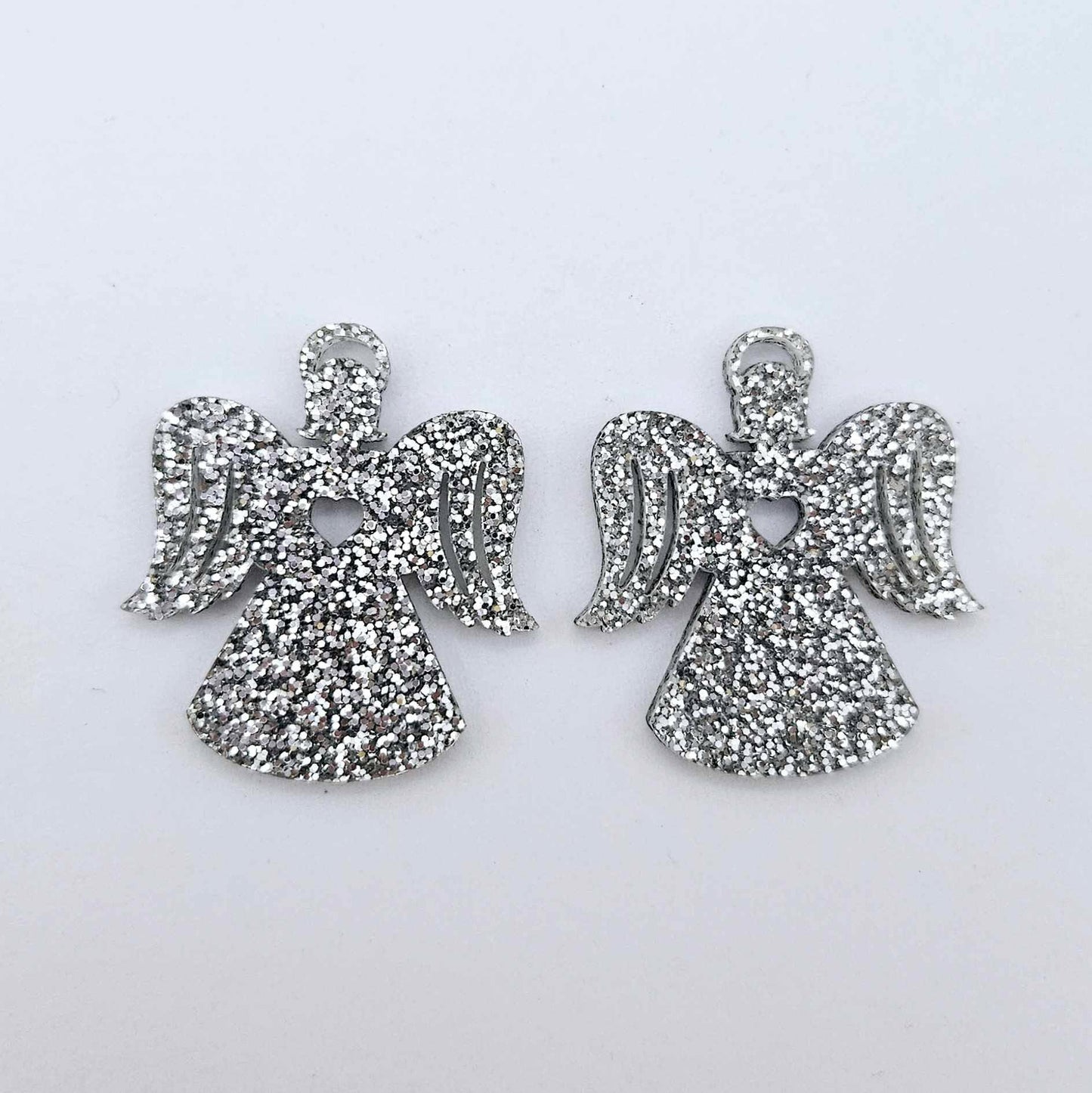 One pair of 32mm silver glitter acrylic angel dangle earring blanks laying flat on a white background