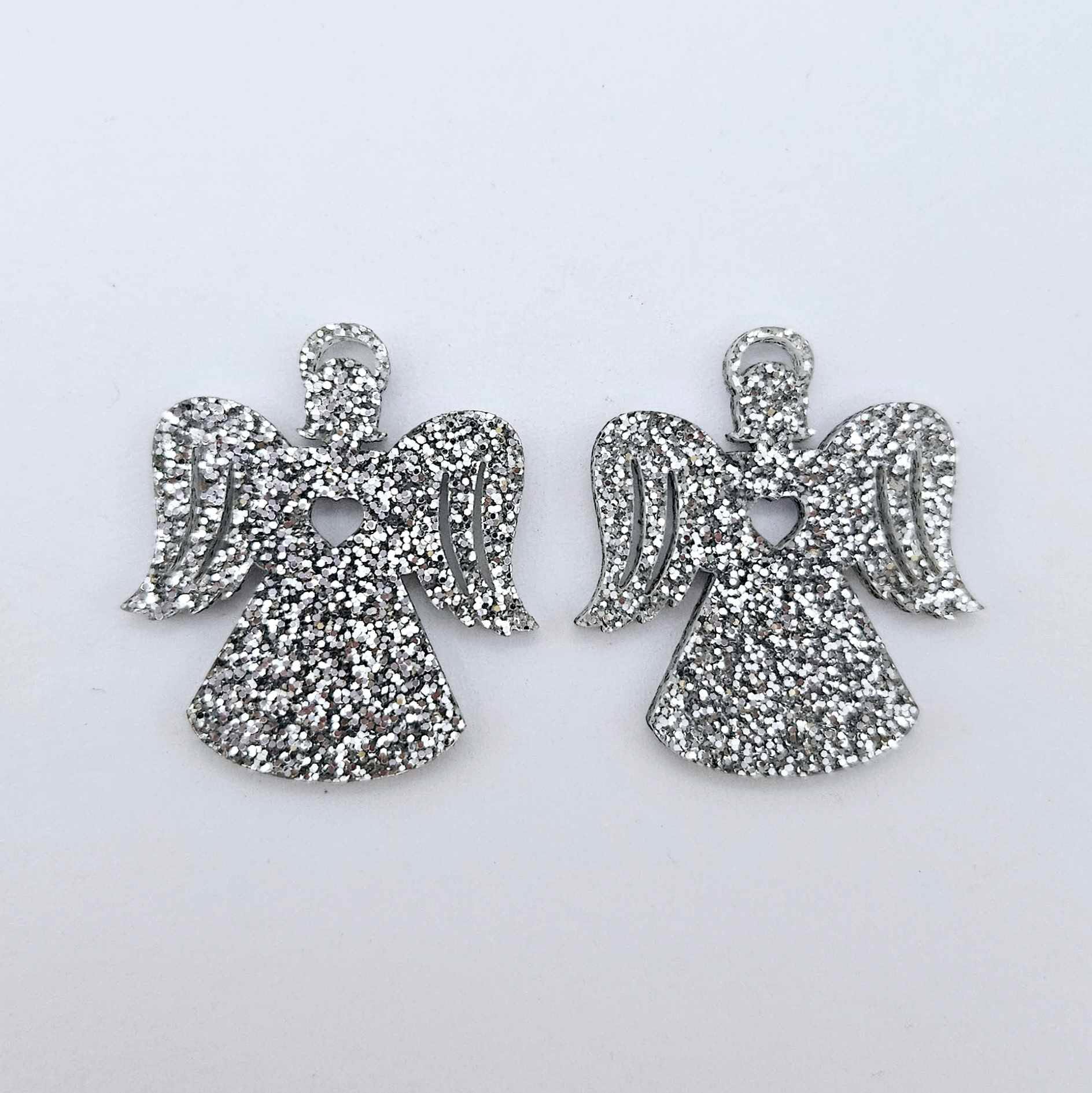 One pair of 32mm silver glitter acrylic angel dangle earring blanks laying flat on a white background