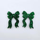 One pair of green glitter acrylic bow dangle earring blanks laying flat