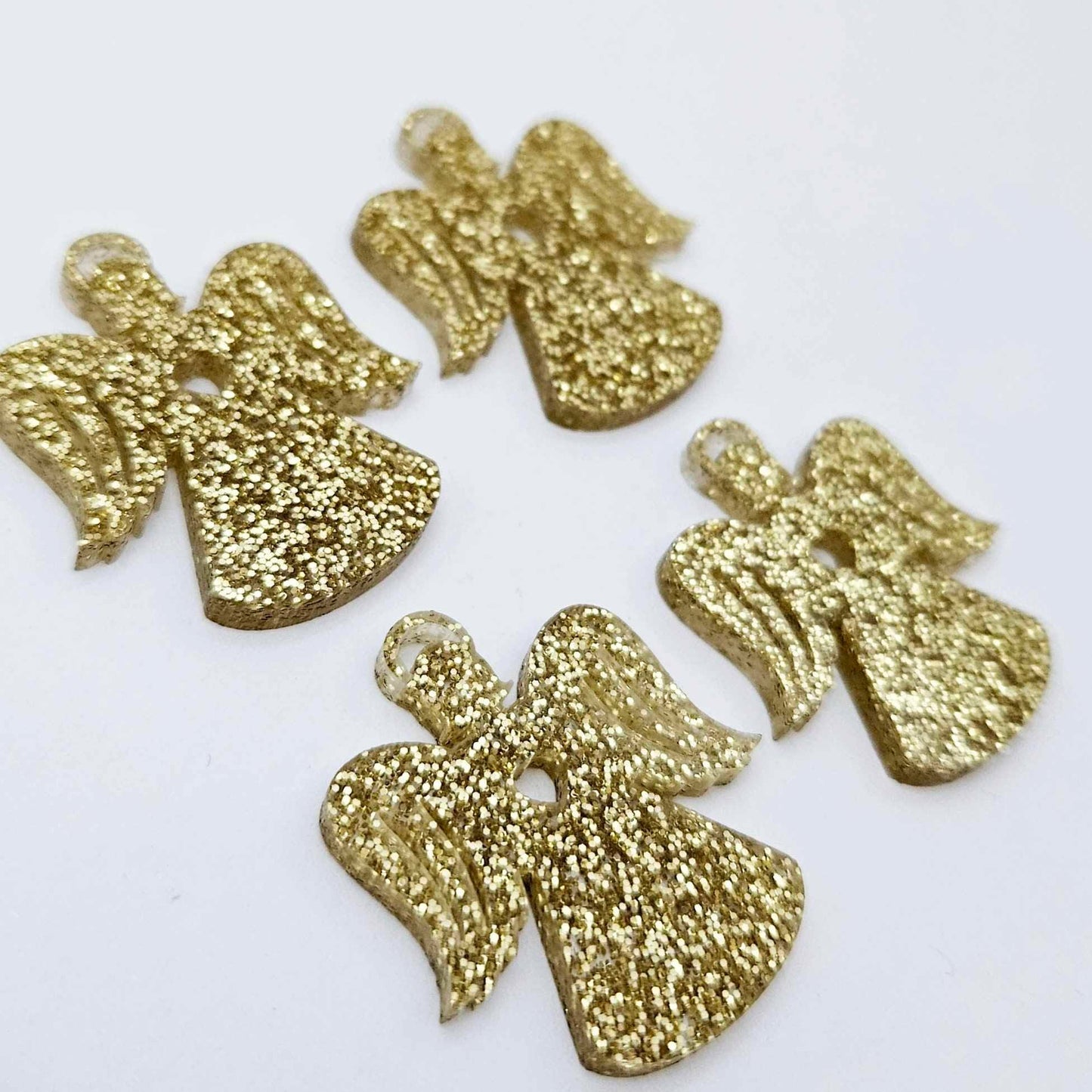 Two pairs of 32mm gold glitter acrylic angel dangle earring blanks laying flat on a white background