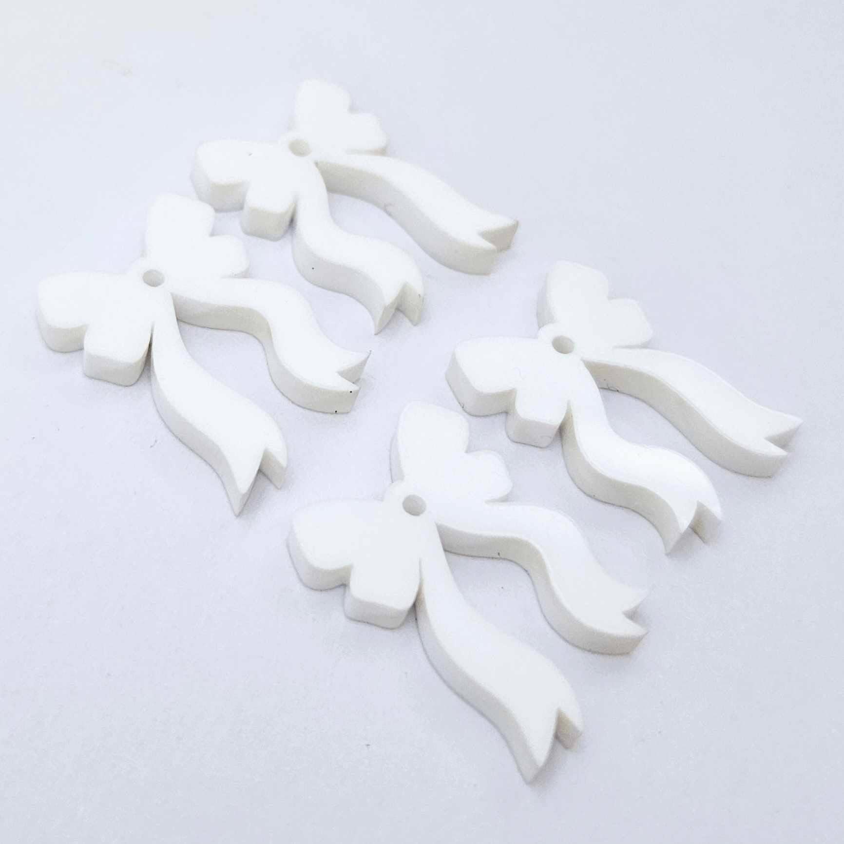 Two pairs of white acrylic bow dangle  earring blanks laying flat