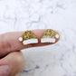 One pair of paint-filled gold glitter acrylic Santa hat stud blanks (no hole) shown on a finger for size reference