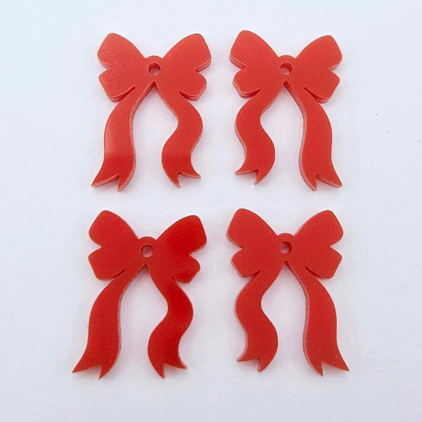 Two pairs of solid red acrylic bow dangle earring blanks laying flat