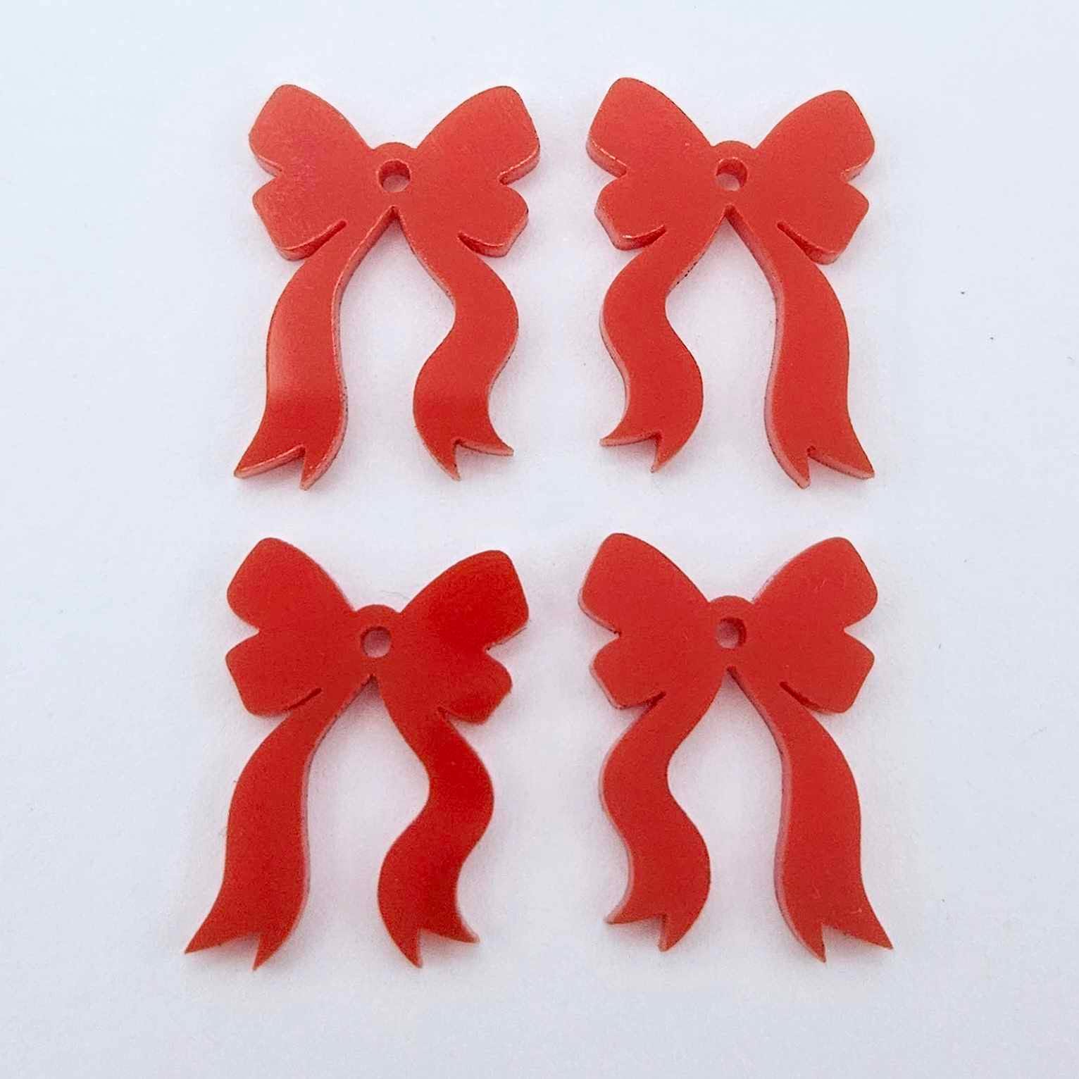 Two pairs of solid red acrylic bow dangle earring blanks laying flat