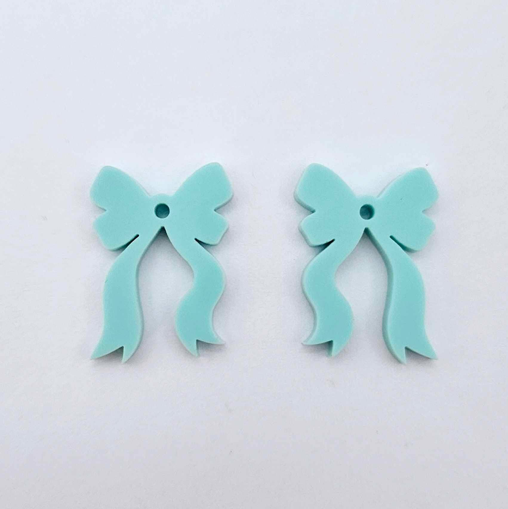 One pair of pastel aqua acrylic bow dangle earring blanks laying flat