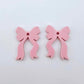 One pair of pastel pink acrylic bow dangle earring blanks laying flat