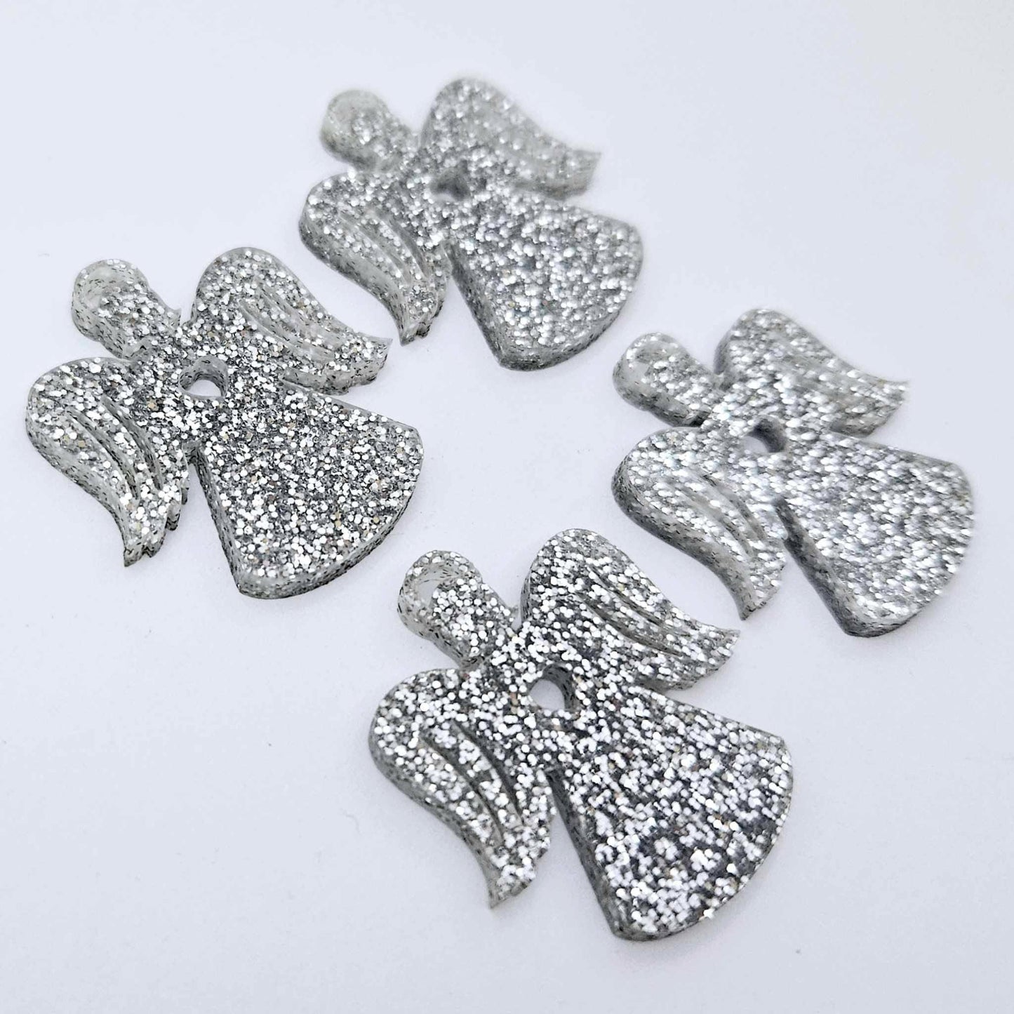 Two pairs of 32mm silver glitter acrylic angel dangle earring blanks laying flat on a white background