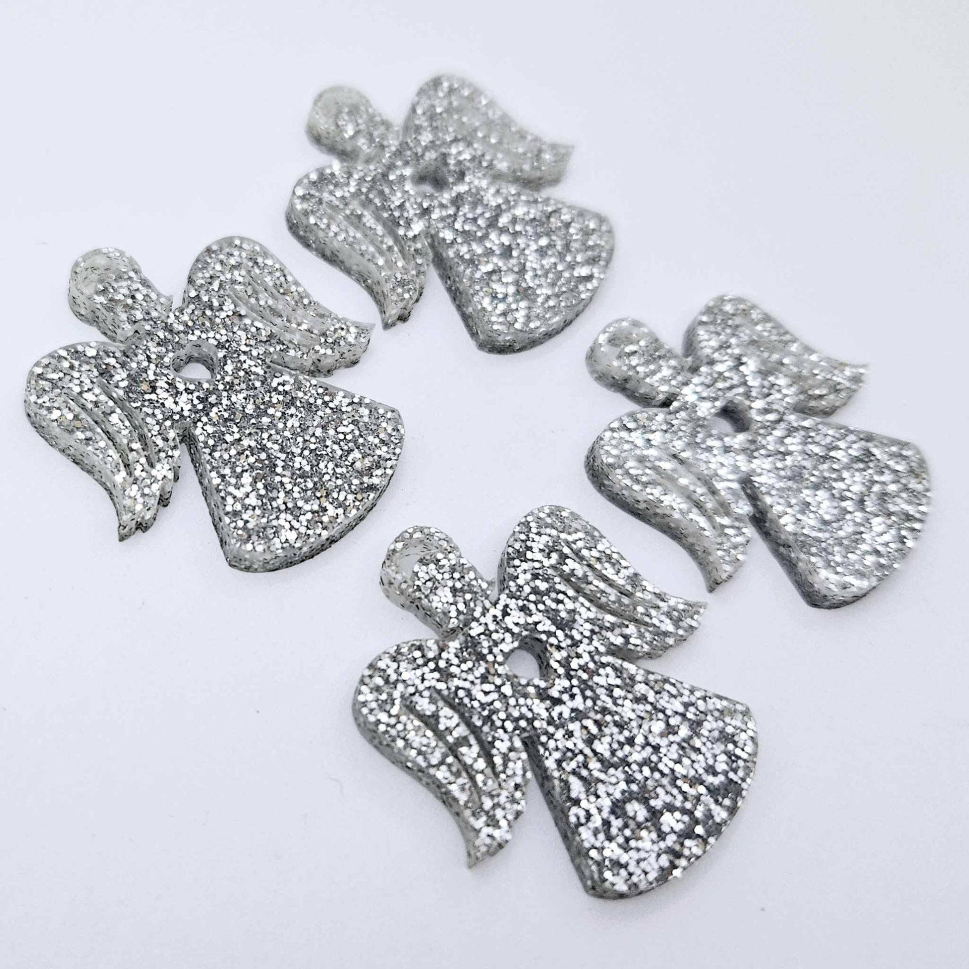 Two pairs of 32mm silver glitter acrylic angel dangle earring blanks laying flat on a white background