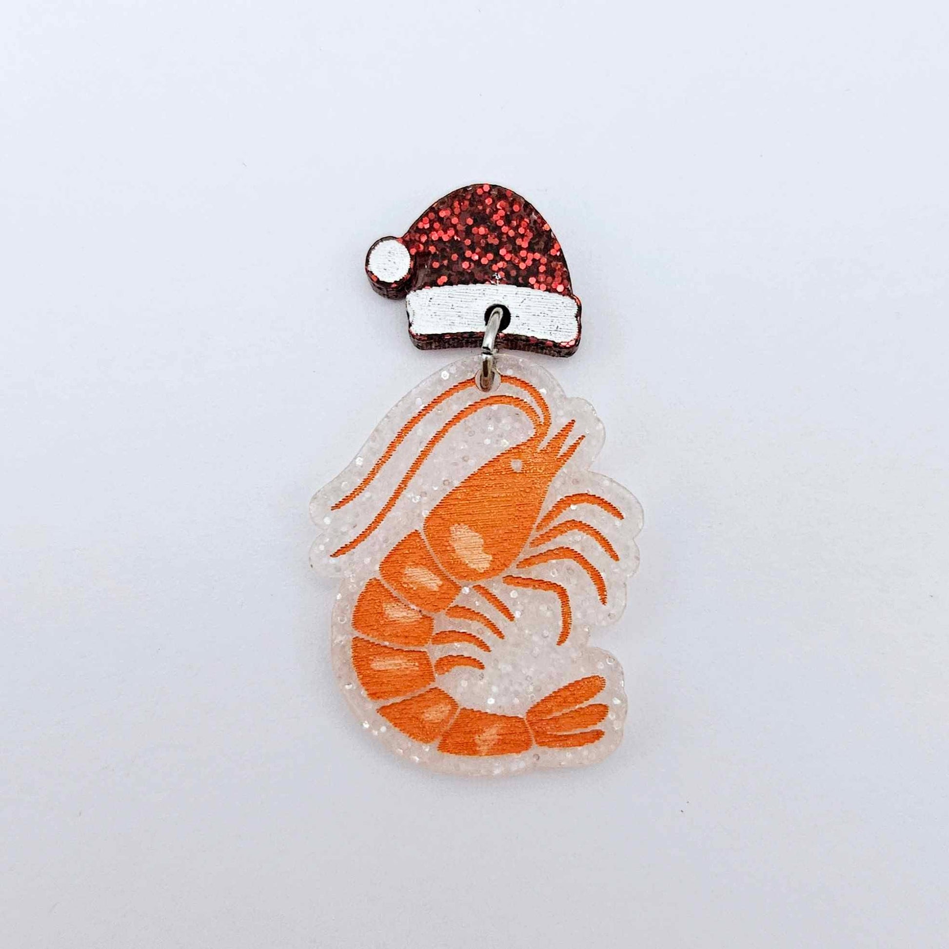 One fairy dust glitter acrylic prawn dangle earring blank assembled with a Santa Hat Topper, shown as a festive Australian Christmas earring
