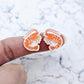 One pair of paint-filled White Marble acrylic prawn stud earring blanks shown on a finger for size reference