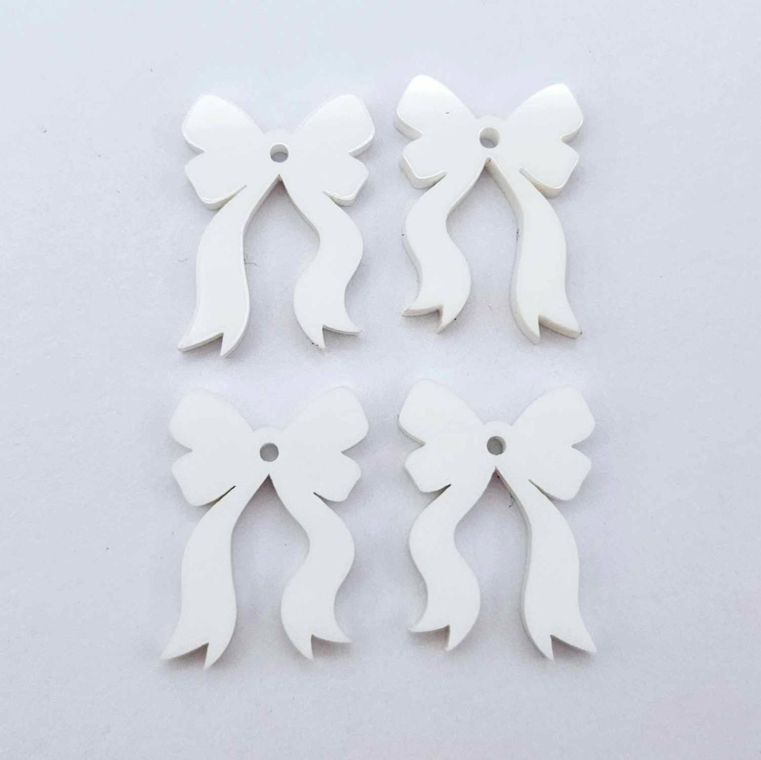Two pairs of white acrylic bow dangle  earring blanks laying flat