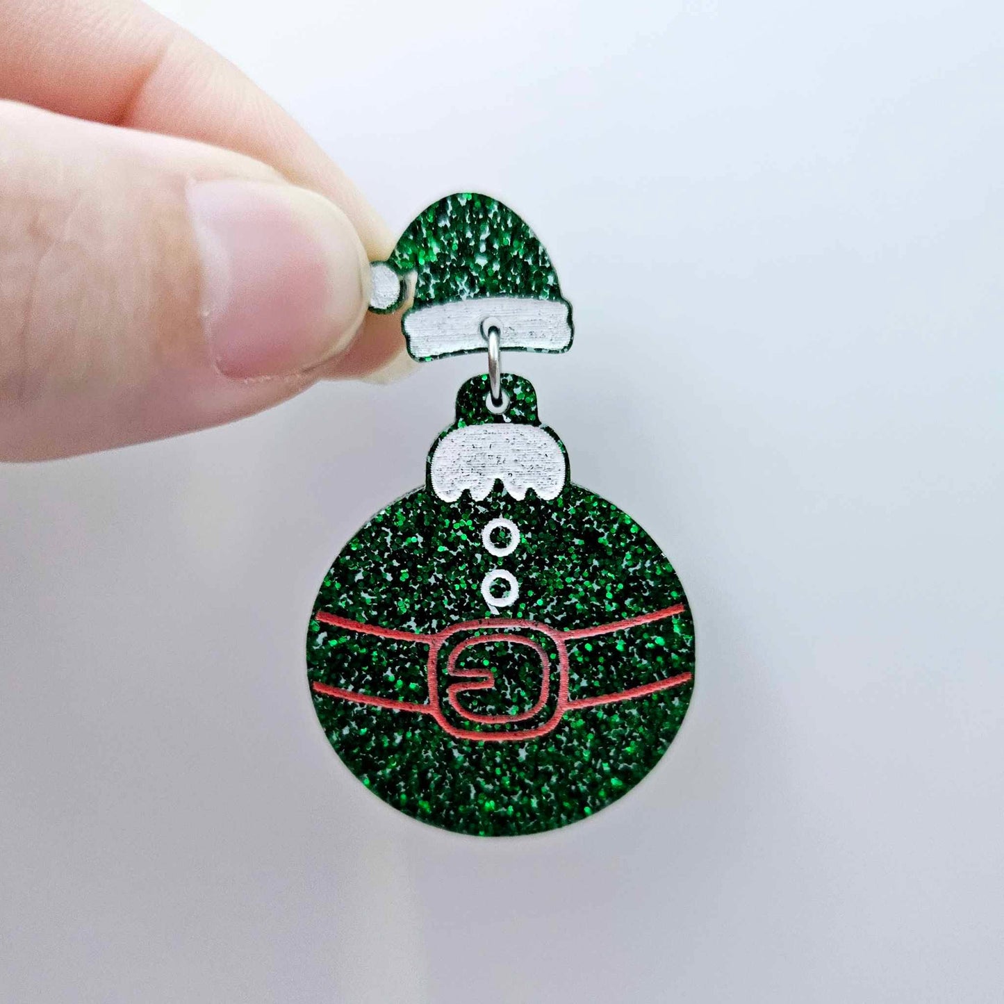 One green glitter Santa hat topper attached to a Christmas Santa Bauble dangle, shown as a finished festive earring design