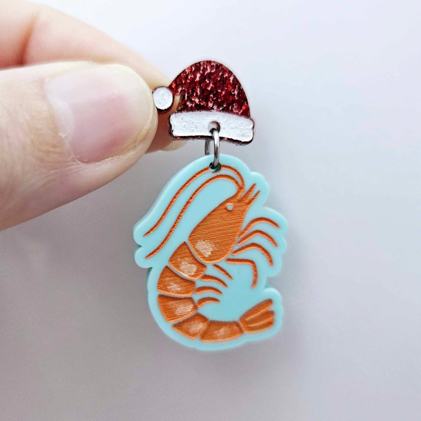 One pastel aqua acrylic prawn dangle earring blank assembled with a Santa Hat Topper, shown as a festive Australian Christmas earring