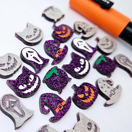 A mixed selection of holographic purple glitter acrylic Halloween stud earring blanks featuring Spooky Cats, Witch’s Cauldrons, Jack-O’-Lanterns, Spooky Face Masks and Witch’s Hats laying flat