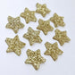 Five pairs of 14mm gold glitter acrylic star earring toppers laying flat