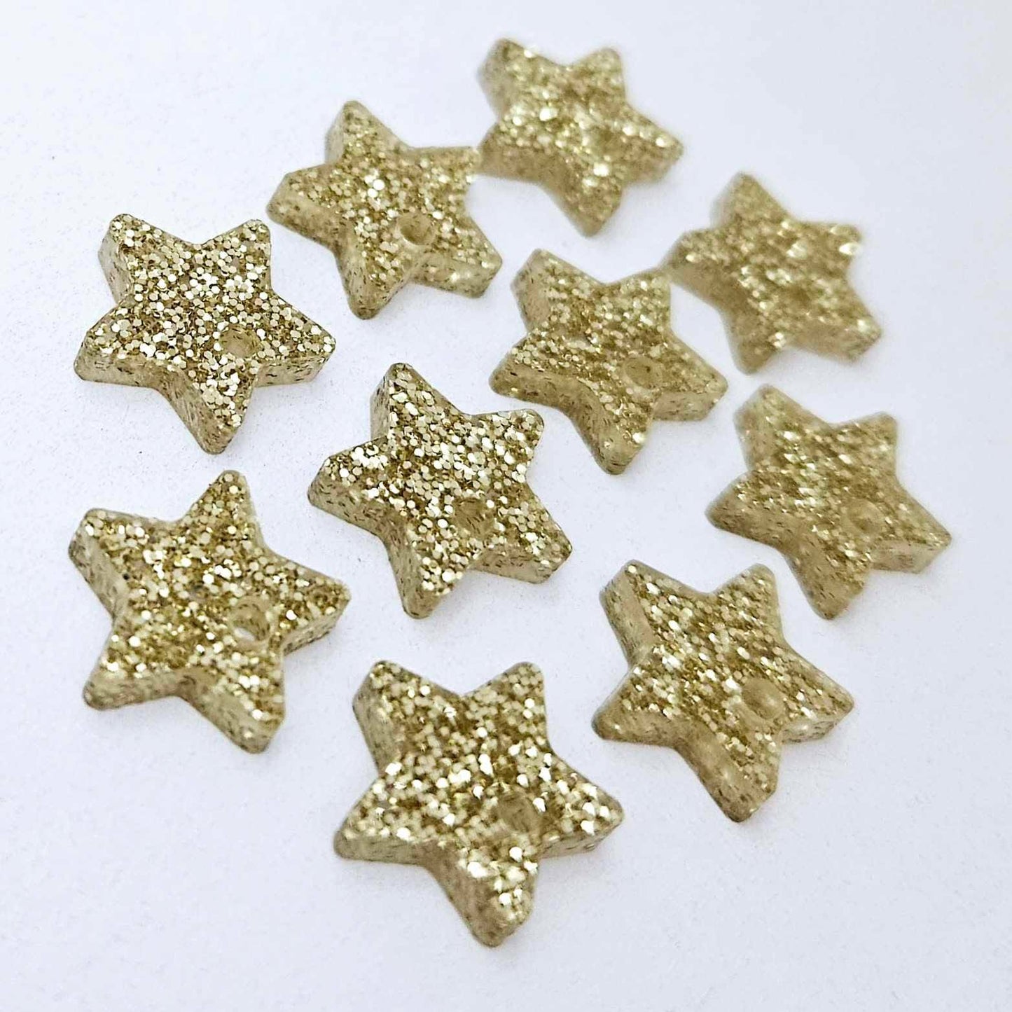 Five pairs of 14mm gold glitter acrylic star earring toppers laying flat