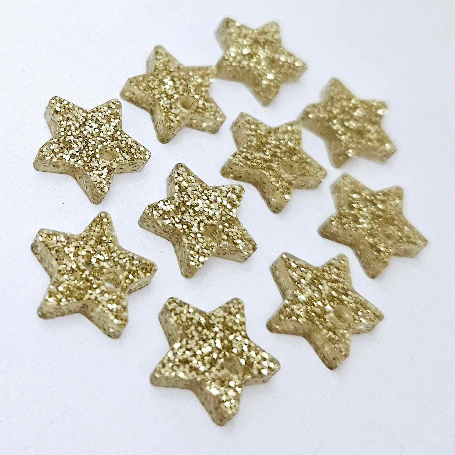 Five pairs of 14mm gold glitter acrylic star earring toppers laying flat