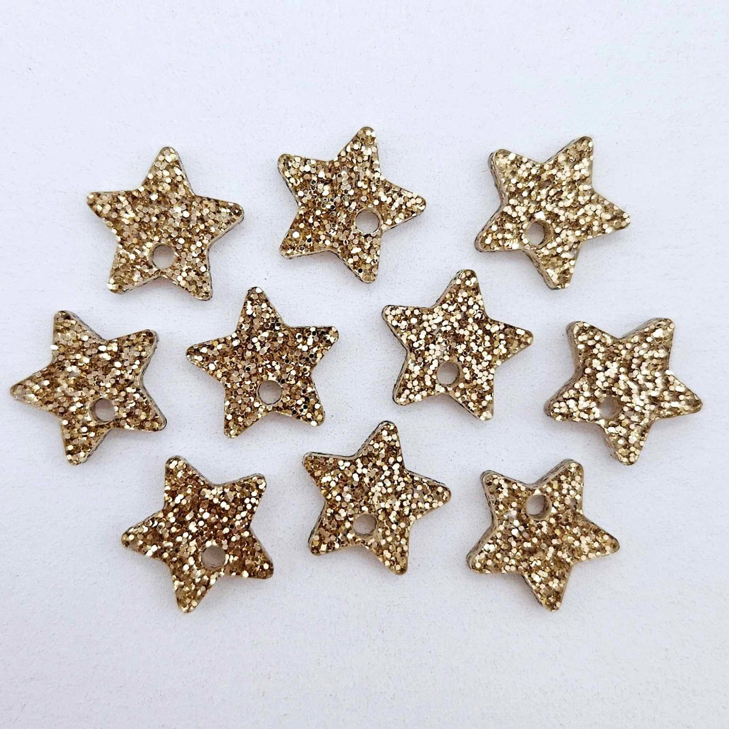 Five pairs of 14mm rose gold glitter acrylic star earring toppers laying flat