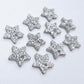Five pairs of 14mm silver glitter acrylic star earring toppers laying flat
