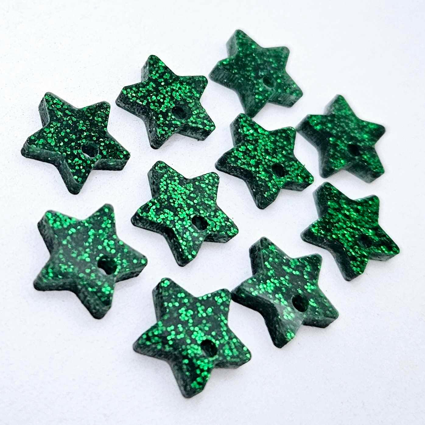 Five pairs of 14mm green glitter acrylic star earring toppers laying flat