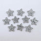 Five pairs of 14mm silver glitter acrylic star earring toppers laying flat