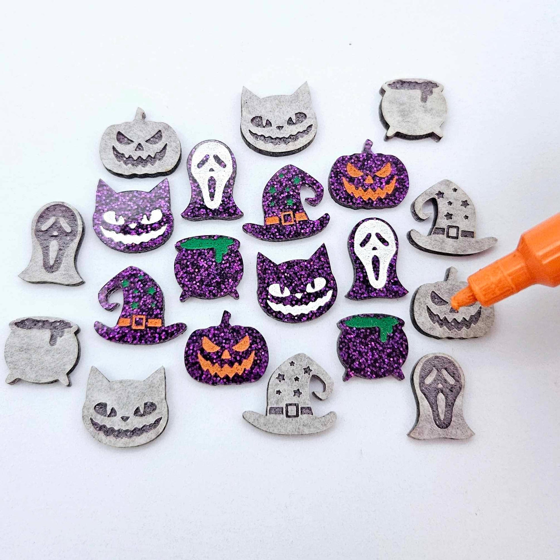 A mixed selection of holographic purple glitter acrylic Halloween stud earring blanks featuring Spooky Cats, Witch’s Cauldrons, Jack-O’-Lanterns, Spooky Face Masks and Witch’s Hats laying flat