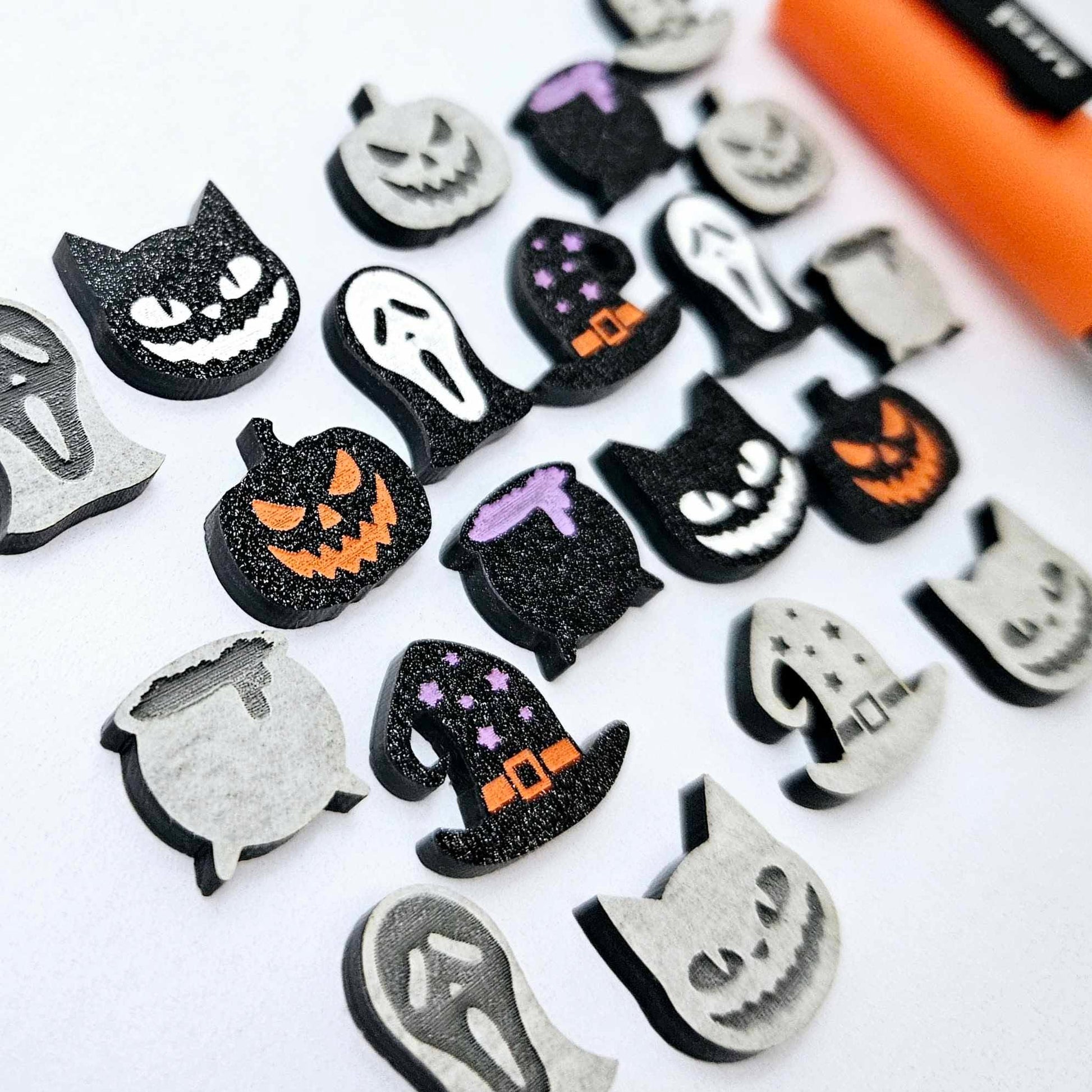 A mixed selection of black glitter acrylic Halloween stud earring blanks featuring Spooky Cats, Witch’s Cauldrons, Jack-O’-Lanterns, Spooky Face Masks and Witch’s Hats laying flat