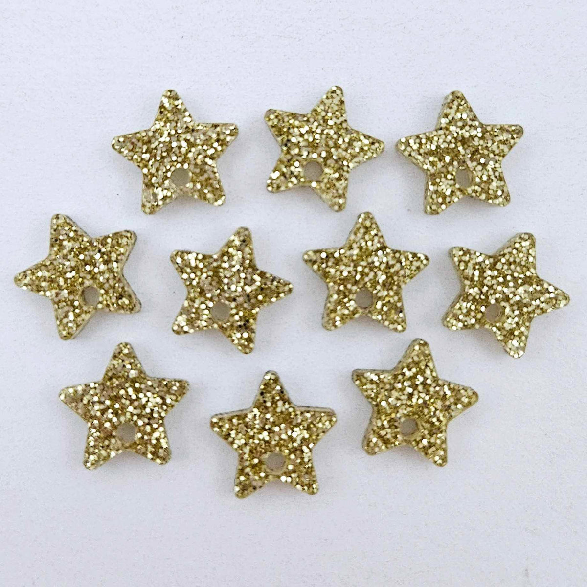 Five pairs of 14mm gold glitter acrylic star earring toppers laying flat