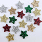 A selection of 14mm fine glitter acrylic star earring toppers in gold, silver, green, red and rose gold glitter laying flat