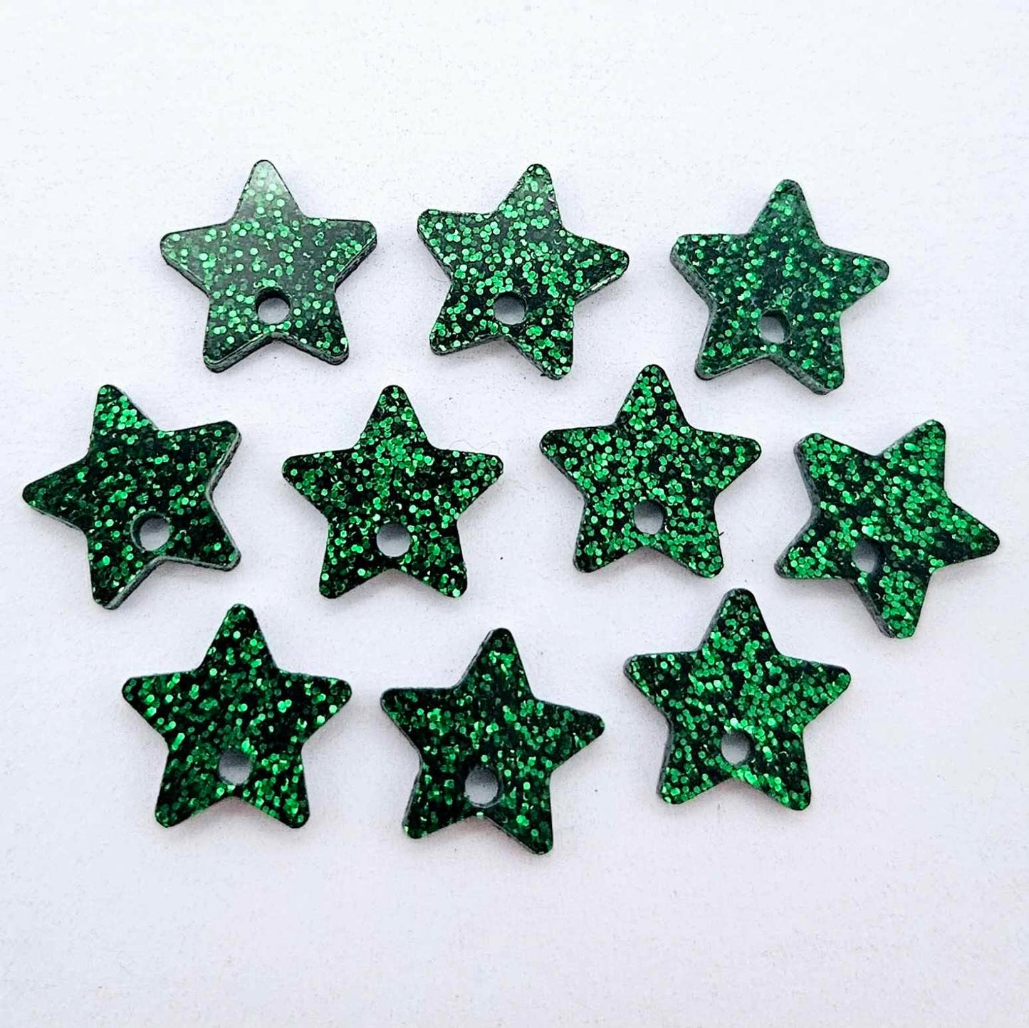 Five pairs of 14mm green glitter acrylic star earring toppers laying flat