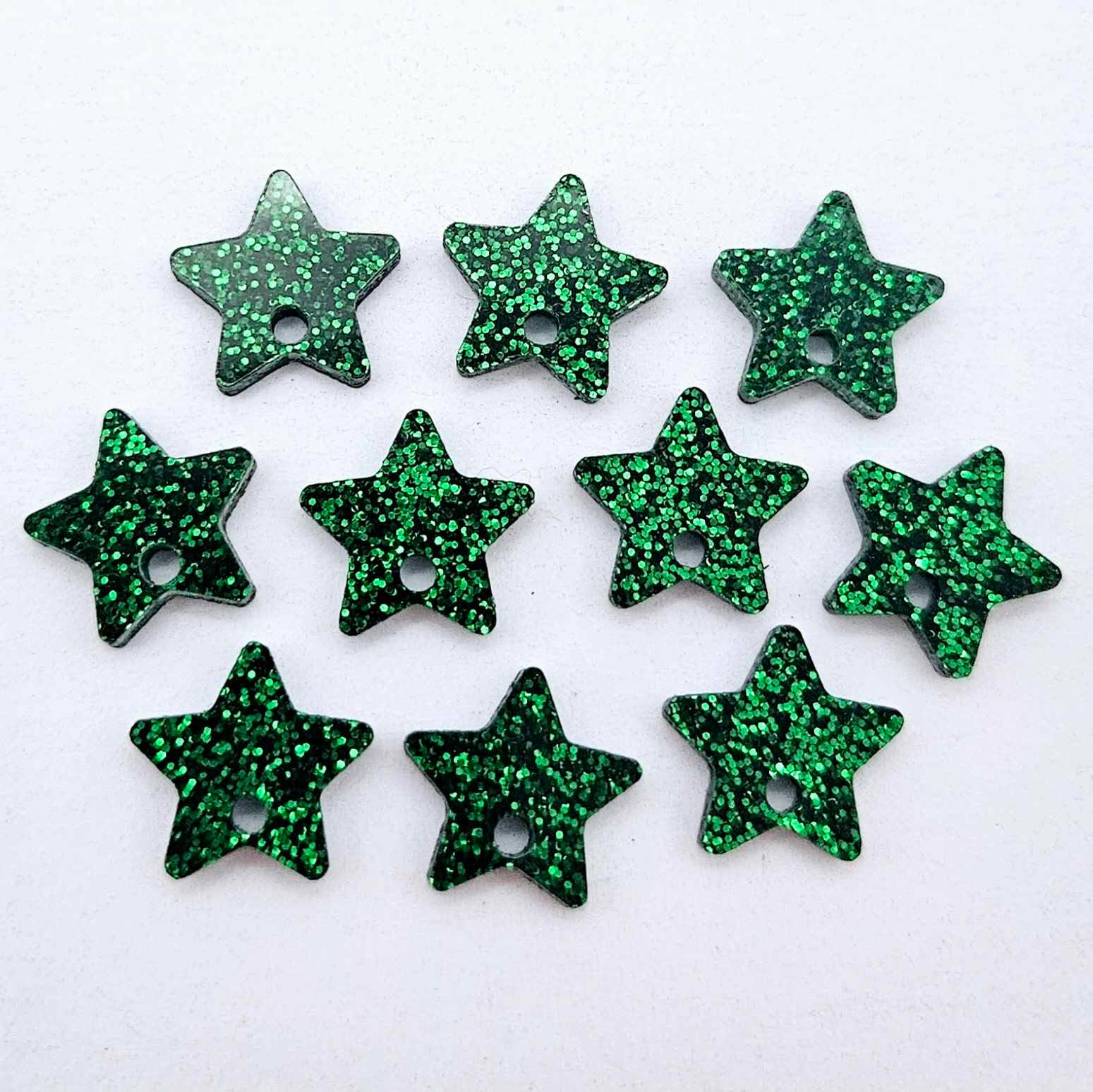 Five pairs of 14mm green glitter acrylic star earring toppers laying flat