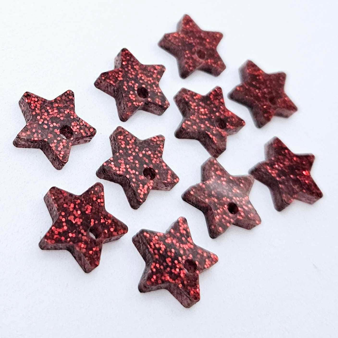 Five pairs of 14mm red glitter acrylic star earring toppers laying flat