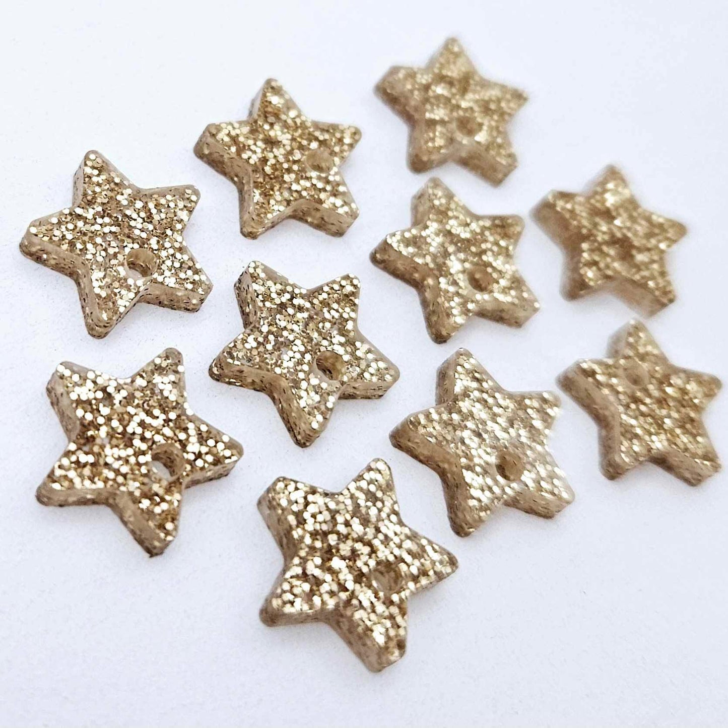 Five pairs of 14mm rose gold glitter acrylic star earring toppers laying flat