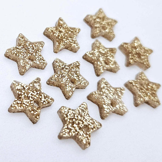 Five pairs of 14mm rose gold glitter acrylic star earring toppers laying flat