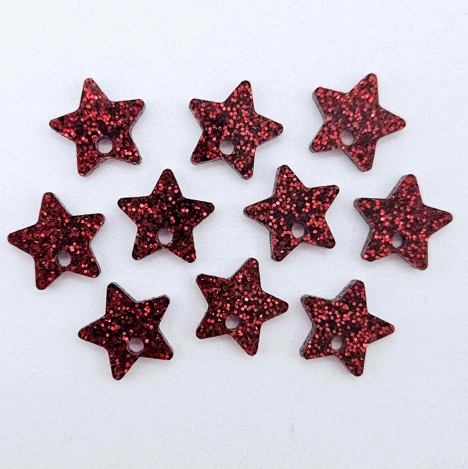 Five pairs of 14mm red glitter acrylic star earring toppers laying flat