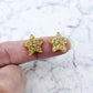 One pair of 14mm gold glitter acrylic star stud earring blanks shown on a finger for size reference