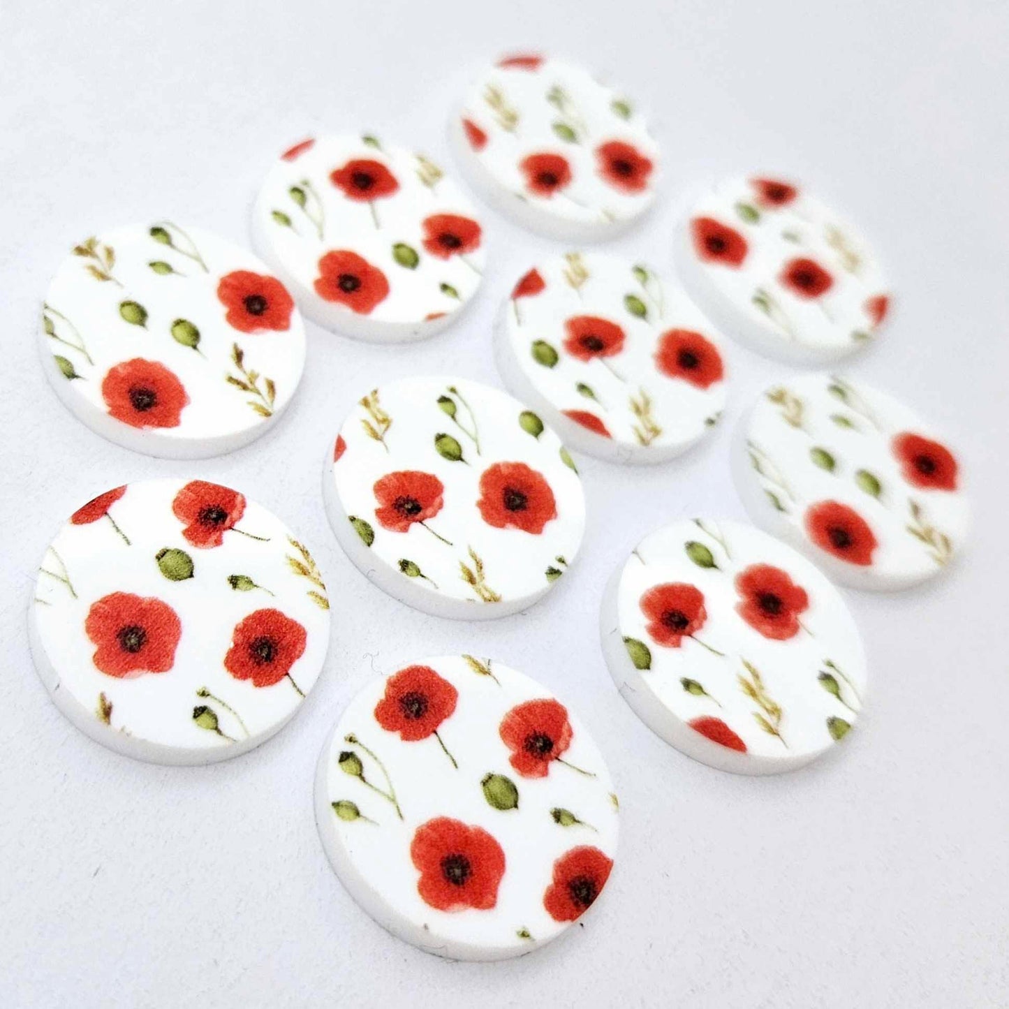 Multiple 20mm Poppy UV printed stud earring blanks featuring detailed poppy blooms and green foliage on white acrylic laying flat.