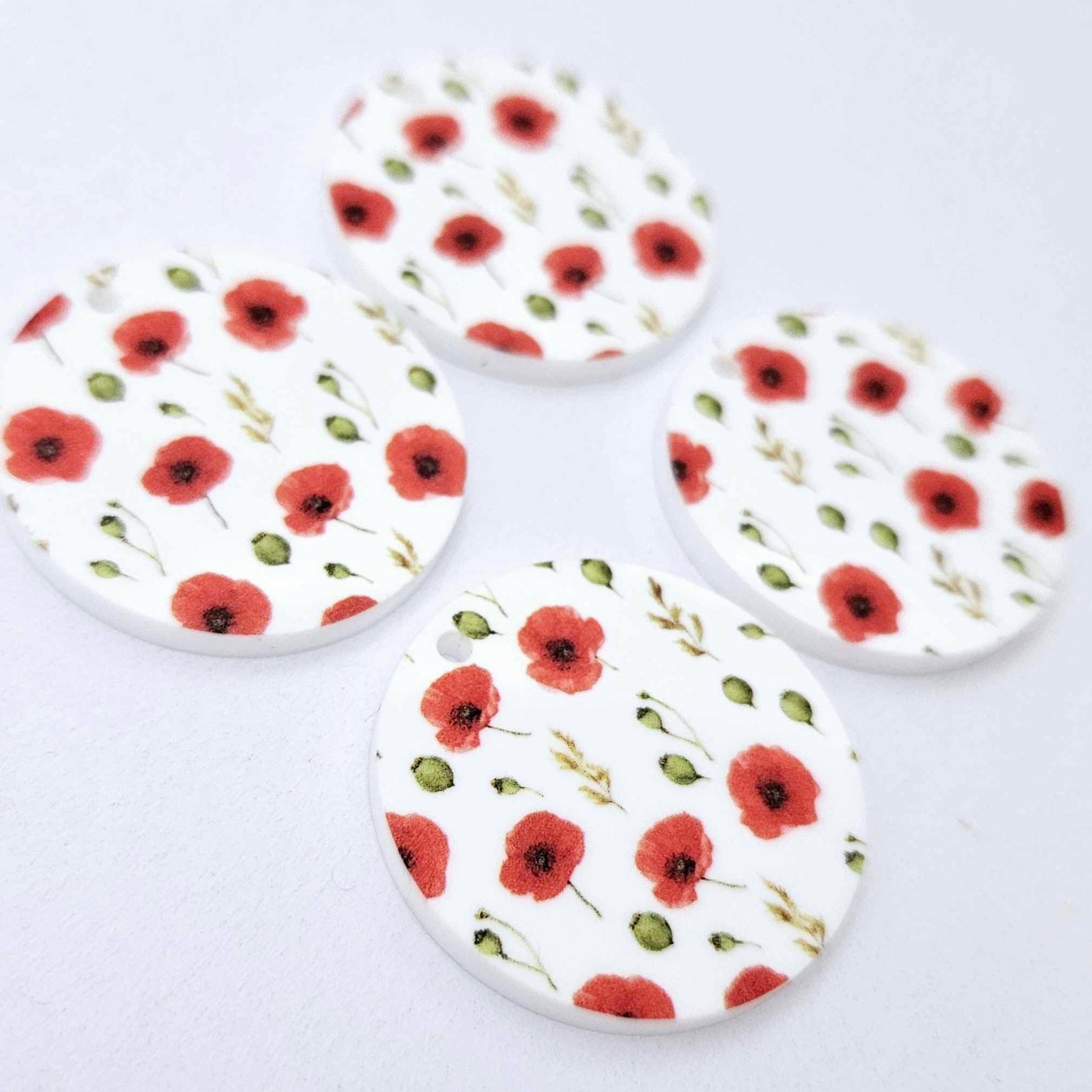 Two pairs of 32mm Poppy UV printed circle dangle earring blanks featuring detailed red poppies and green foliage on white acrylic laying flat.