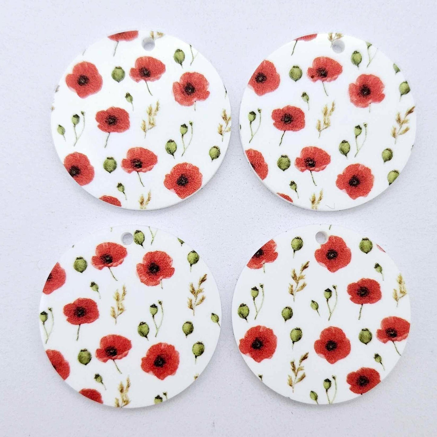 Two pairs of 32mm Poppy UV printed circle dangle earring blanks featuring detailed red poppies and green foliage on white acrylic laying flat.